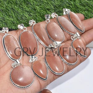 Puede incluir: Una colecci&oacute;n de 10 colgantes de piedra de sol con engastes de plata. Los colgantes son de forma ovalada y de l&aacute;grima y tienen un color naranja claro.