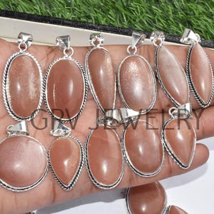 Puede incluir: Una colecci&oacute;n de diez colgantes de plata con piedras preciosas de piedra de sol. Los colgantes son de forma ovalada y de l&aacute;grima y tienen un engaste de plata. La piedra de sol es de color naranja claro con un efecto brillante.