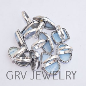 May include: A group of silver rings with blue opal stones. The rings are stacked on top of each other and the stones are facing up. The rings are all different shapes and sizes.
