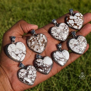 May include: Seven heart-shaped pendants featuring white stone with brown veining, each set in a silver-toned metal frame with a decorative bail. The pendants display a marbled pattern and are arranged together, showcasing the natural stone variations.