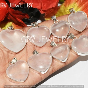 May include: Seven heart-shaped rose quartz pendants with silver settings. The pendants are arranged in a hand, with the tips of the hearts pointing towards the viewer.