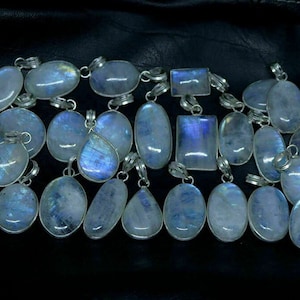 May include: A collection of 20 iridescent moonstone pendants with silver settings. The stones are oval, teardrop, and rectangular shapes.