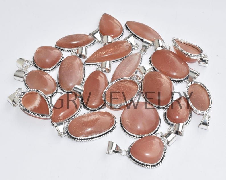 Puede incluir: Una colecci&oacute;n de 17 colgantes de piedra de sol con engastes de plata. Los colgantes son de diversas formas y tama&ntilde;os, con una mezcla de tonos naranja, rojo y marr&oacute;n.