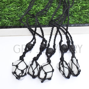 Puede incluir: Cinco collares de cristal blanco con cordón de macramé negro y cuentas de lava negra. Los collares están anudados y tienen un colgante de cristal.