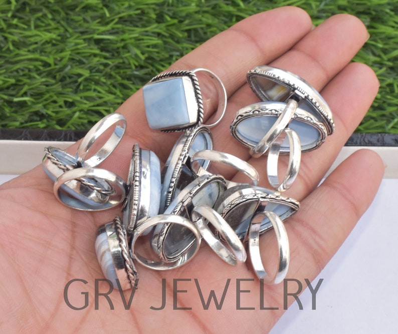 May include: A collection of silver rings with blue opal stones. The rings are in various shapes and sizes, and some have intricate designs.