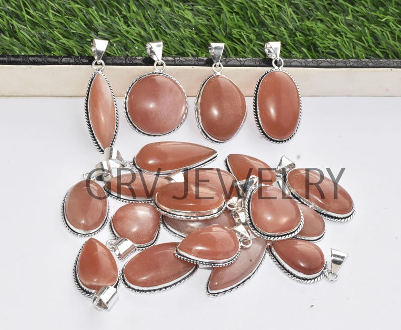 Puede incluir: Una colecci&oacute;n de 14 colgantes de plata con piedras preciosas de piedra de sol naranja de diferentes formas y tama&ntilde;os.