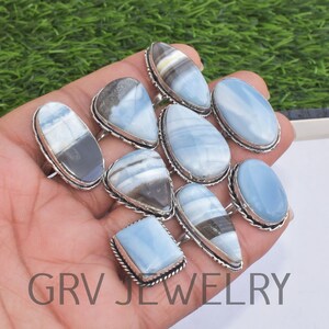 May include: A collection of ten silver rings with blue opal gemstones. The rings feature various shapes and sizes of opal stones, including oval, teardrop, and square.