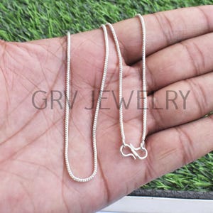 Puede incluir: Un collar de cadena de plata con cierre de langosta. La cadena es fina y tiene un dise&ntilde;o delicado, ligeramente texturizado.