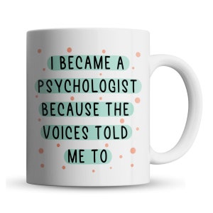 Peut inclure: Une tasse à café en céramique blanche avec un motif noir et turquoise. La tasse porte l'inscription "Je suis devenu psychologue parce que les voix me l'ont dit".