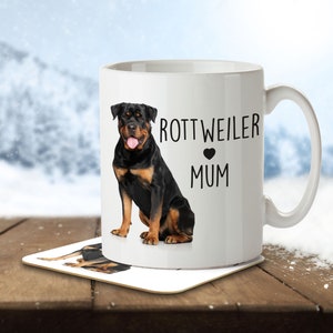 Op de afbeelding: Witte keramische mok met een afbeelding van een zwarte Rottweiler-hond en de tekst "Rottweiler Mum" met een zwart hart.