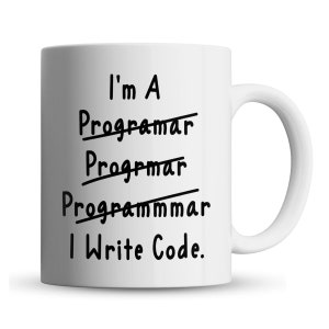 May include: White ceramic mug with the text "I'm A Programmer I Write Code." The words "Programmar", "Progrmar", and "Programmmar" are crossed out. The mug has a curved handle and is set against a white background.