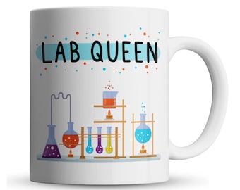May include: White ceramic mug with a blue and white stripe and the text "LAB QUEEN" in black. The mug features a cartoon illustration of a chemistry lab setup with beakers, flasks, and test tubes.