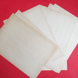 May include: A stack of six blank, off-white paper sheets on a red background.