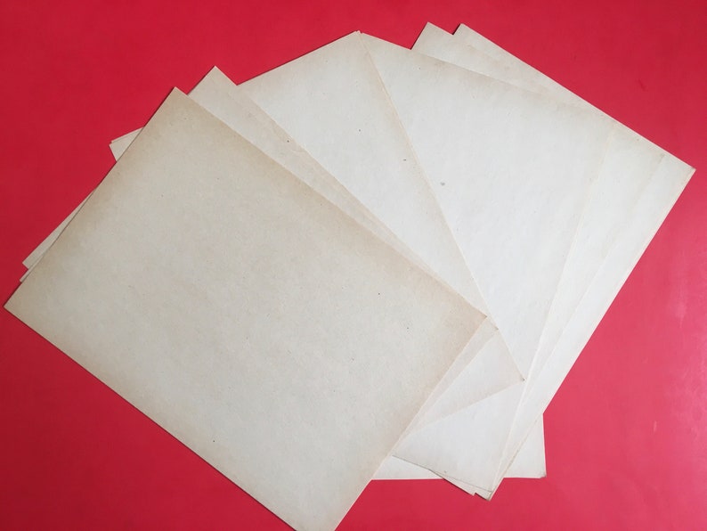 May include: A stack of six blank, off-white paper sheets on a red background.