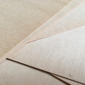 May include: Close-up of several sheets of light brown craft paper stacked on top of each other.
