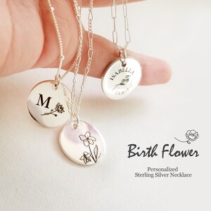 May include: Three sterling silver necklaces with personalized pendants. The pendants feature a flower design, an initial "M", and the name "Isabella" with a birthdate. The necklaces are on a white background with the text "Birth Flower Personalized Sterling Silver Necklace".