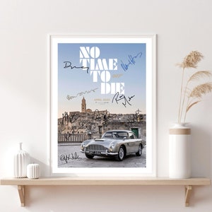 May include: A movie poster for the James Bond film "No Time To Die" featuring a silver Aston Martin DB5 driving through a small Italian town. The poster is signed by the cast and crew, including Daniel Craig, Rami Malek, and Lea Seydoux.