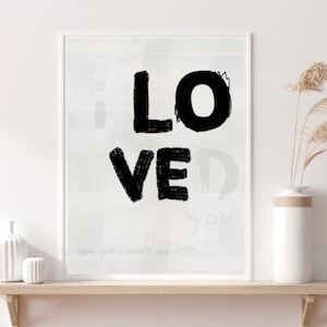 Könnte beinhalten: Schwarz-weißes Typografie-Druckbild mit dem Wort "LOVE" in großen, fetten, handgeschriebenen Buchstaben. Der Hintergrund ist hellgrau mit einer subtilen Textur. Der Text "You just couldn't see it..." ist am unteren Rand des Drucks sichtbar.
