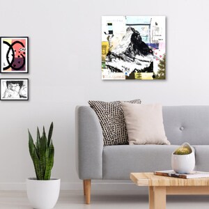 May include: Abstract art print featuring a black and white mountain illustration with colorful collage elements. Two framed prints with graphic designs are displayed on the wall. A gray sofa with decorative pillows and a wooden coffee table complete the scene.