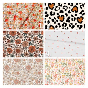 May include: A collection of six fabric swatches with various floral and animal print designs. The fabrics feature patterns of red, orange, and yellow flowers, a leopard print, small red hearts, and other floral arrangements in neutral tones.