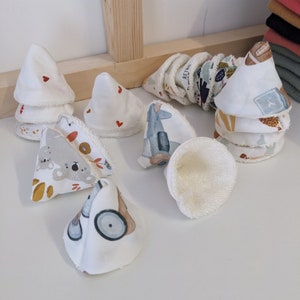 Peut inclure: Un ensemble de 10 disques démaquillants réutilisables en tissu de coton doux. Les disques sont de différentes couleurs et motifs, dont un koala, un avion et une voiture. Les disques sont en forme de cônes et ont une doublure en tissu éponge blanc.