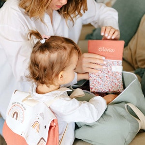 Maman, Lana qui remplissent le sac polochon avec le protège carnet de santé. Lana porte aussi un sac à dos personnalisé en double gaze de coton