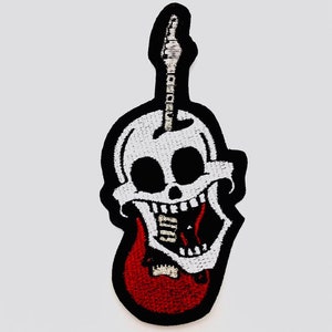 Könnte beinhalten: Ein gestickter schwarzer und weißer Aufnäher mit einem Totenkopf und einem roten Gitarrenkörper. Der Schädel grinst mit offenem Mund und der Gitarrenhals ragt aus dem Kopf heraus.