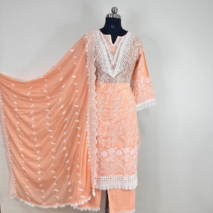 May include: Peach colored embroidered dress with white lace trim and a matching peach colored dupatta. The dress has a V-neckline and 3/4 sleeves.