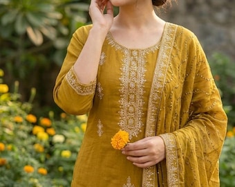 May include: Mustard-colored salwar kameez with intricate gold embroidery. The ensemble includes a long-sleeved tunic, matching pants, and a dupatta. The outfit is adorned with detailed floral patterns and is suitable for festive occasions.