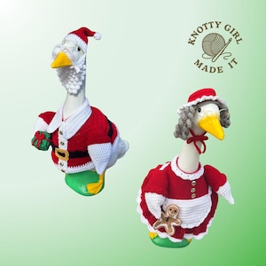 Pode incluir: Duas figuras decorativas de ganso vestidas com trajes natalinos. Uma usa uma roupa de Papai Noel com chapéu vermelho, barba branca e um presente. A outra está vestida de Mamãe Noel, segurando um homem de gengibre.