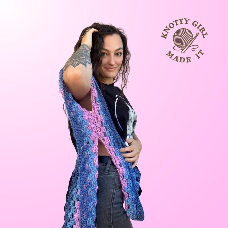 Pode incluir: Um xale de croch&ecirc; azul e rosa com um design aberto. O xale &eacute; feito com uma variedade de fios azuis e rosa, criando um padr&atilde;o texturizado e colorido. A imagem tamb&eacute;m inclui o texto "Knotty Girl Made It".