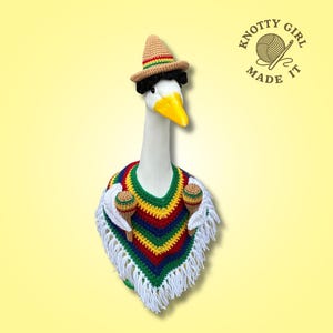Könnte beinhalten: Eine weiße Gans mit gehäkeltem Sombrero, Perücke und Poncho mit Maracas. Der Poncho ist rot, gelb, grün und blau mit weißem Fransen. Das Bild enthält den Text "KNOTTY GIRL MADE IT".