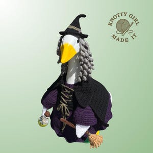 May include: A goose dressed as a witch, wearing a black hat with a gold band, a black cape, and a purple dress. The goose holds a broom and a small potion bottle. The image includes the text "KNOTTY GIRL MADE IT".