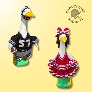 May include: Two white goose figurines wearing crocheted outfits. One goose wears a black and white football jersey with the number 57, a helmet, and holds a football. The other goose wears a red and white cheerleader outfit with a bow and pom-poms.