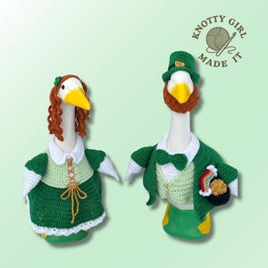 May include: Two goose figurines dressed in crochet outfits. One goose wears a green dress with white trim and a red wig. The other goose is dressed as a leprechaun, with a green jacket, bow tie, and hat, holding a pot of gold.