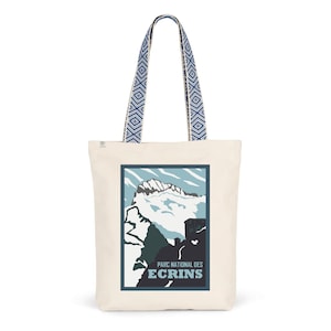 May include: A white canvas tote bag with blue and white patterned straps. The bag features a graphic of a mountain range with the text "Parc National des Ecrins" printed on the front.