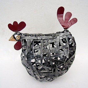May include: A metal chicken sculpture with a grey woven body and red comb and wattles. The chicken is standing on a white surface.