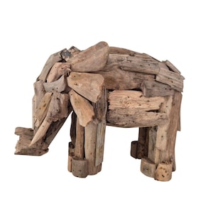 Pu&ograve; includere: Scultura di elefante in legno di deriva. La scultura &egrave; realizzata con vari pezzi di legno di colore naturale, con una proboscide, orecchie e quattro zampe. L'elefante &egrave; posto su uno sfondo bianco.
