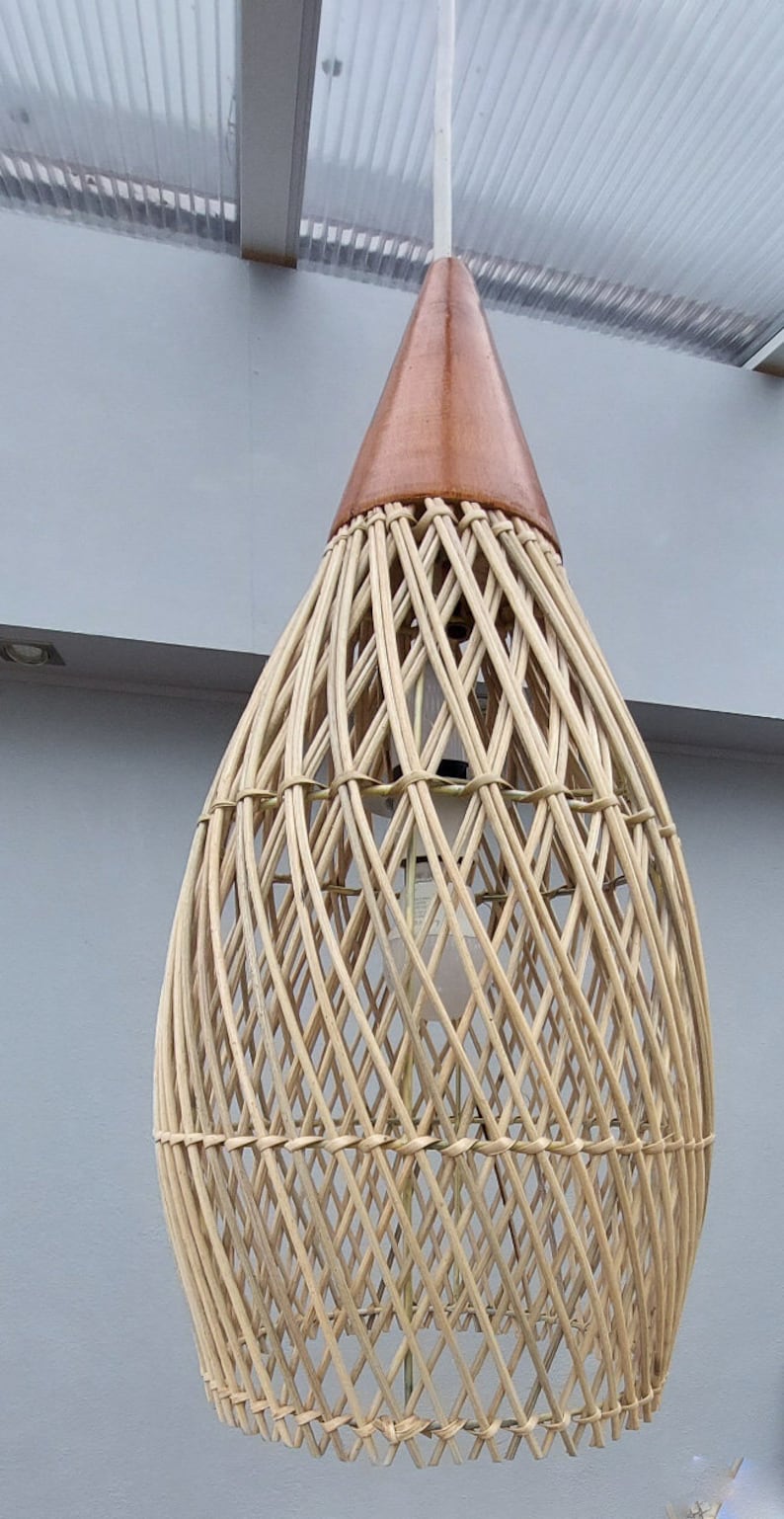 May include: A woven wicker pendant light with a brown wooden top. The light is hanging from a white cord.