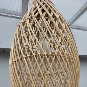 May include: A woven wicker pendant light fixture with a brown top. The light fixture is made of natural materials and has a rustic, bohemian style.