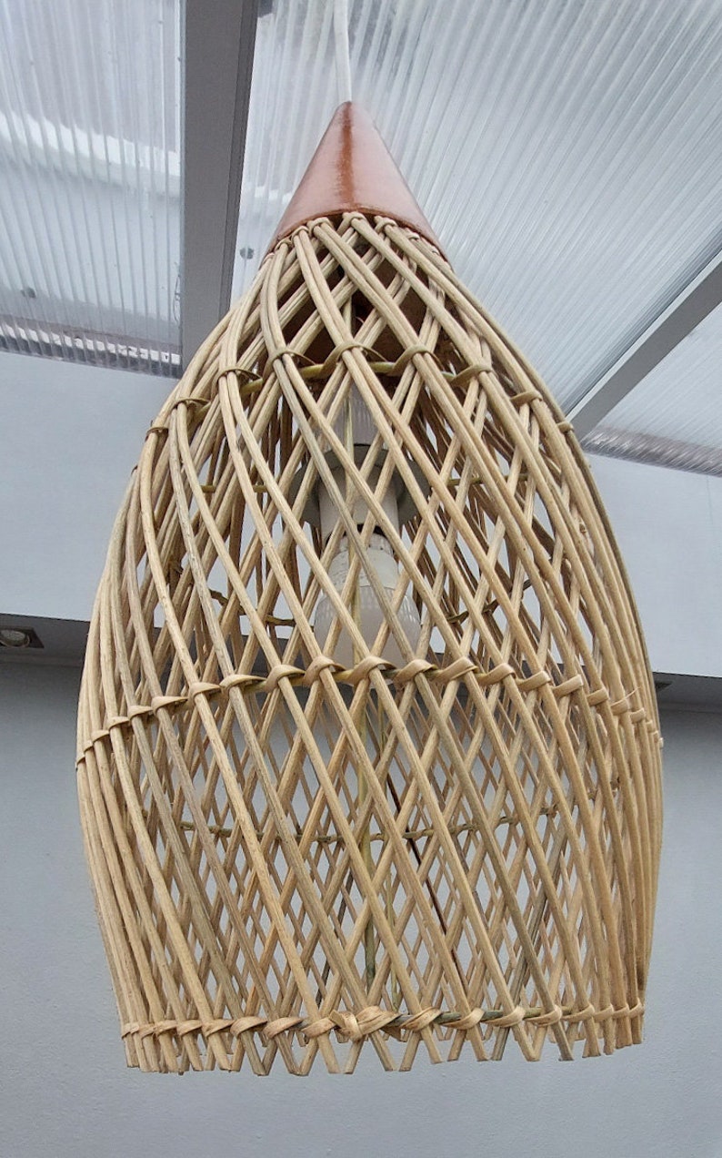 May include: A woven wicker pendant light fixture with a brown top. The light fixture is made of natural materials and has a rustic, bohemian style.