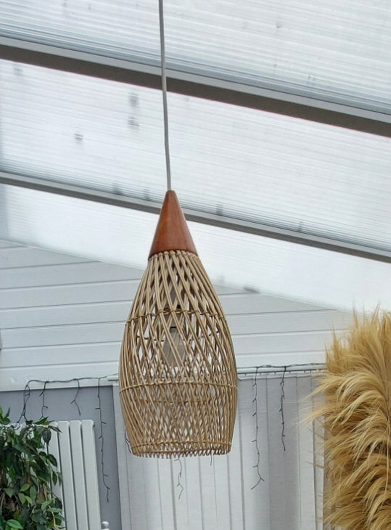 May include: A woven wicker pendant light with a brown wooden top. The light is hanging from a white cord.