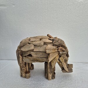 Pu&ograve; includere: Una scultura di elefante in legno realizzata con piccoli pezzi di legno di deriva. L'elefante &egrave; raffigurato di profilo, con la proboscide, le zanne e le grandi orecchie. La scultura &egrave; di colore legno naturale e poggia su quattro robuste zampe.