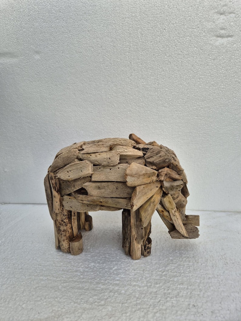 Pu&ograve; includere: Una scultura di elefante in legno realizzata con piccoli pezzi di legno di deriva. L'elefante &egrave; raffigurato di profilo, con la proboscide, le zanne e le grandi orecchie. La scultura &egrave; di colore legno naturale e poggia su quattro robuste zampe.