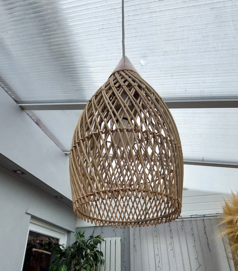 May include: A woven wicker pendant light fixture with a natural brown color. The light fixture is hanging from a white ceiling.