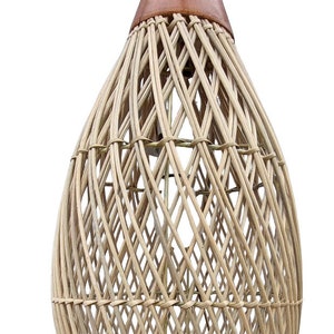 May include: A woven wicker lampshade with a brown leather top. The lampshade is shaped like a teardrop and has a delicate, intricate pattern.