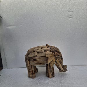 Pu&ograve; includere: Scultura di elefante in legno di deriva. L'elefante &egrave; costruito con piccoli pezzi di legno, mostrando un aspetto naturale e strutturato con venature visibili. Presenta una proboscide, zanne e quattro zampe, mostrando un'estetica rustica e artigianale.