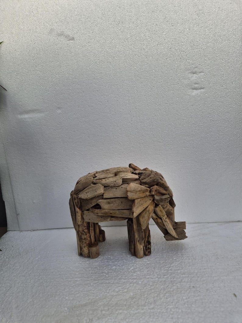 Pu&ograve; includere: Scultura di elefante in legno di deriva. L'elefante &egrave; costruito con piccoli pezzi di legno, mostrando un aspetto naturale e strutturato con venature visibili. Presenta una proboscide, zanne e quattro zampe, mostrando un'estetica rustica e artigianale.