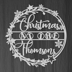 Peut inclure: Guirlande de No&euml;l en bois blanc avec le texte "Christmas at the Thompsons" et un motif floral d&eacute;coratif.