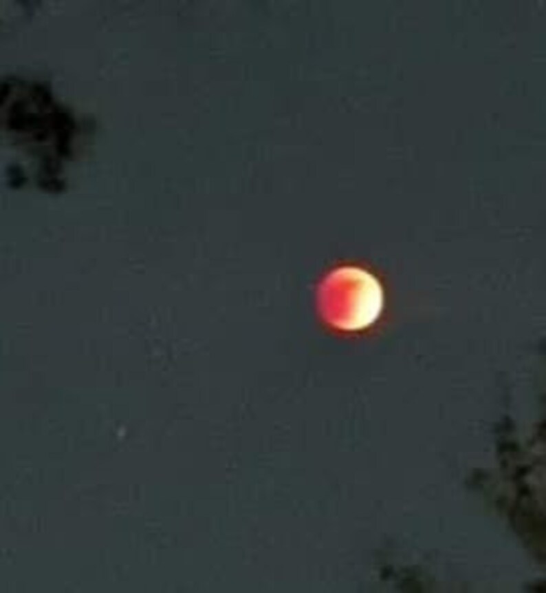 May include: A red moon in the night sky.